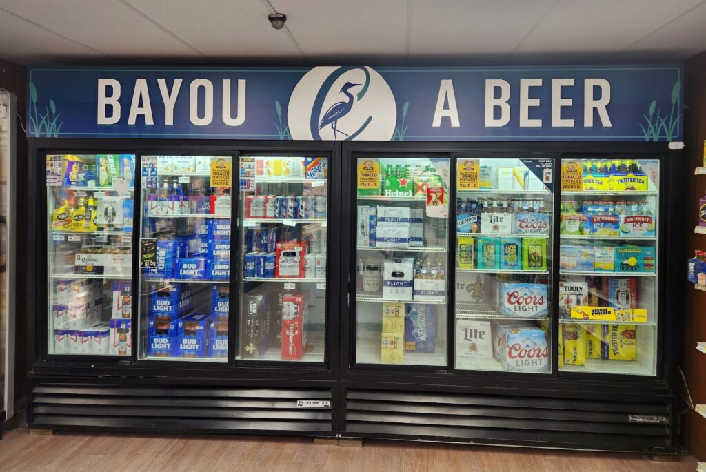 A refrigerated display case stocked with beers sits under a 