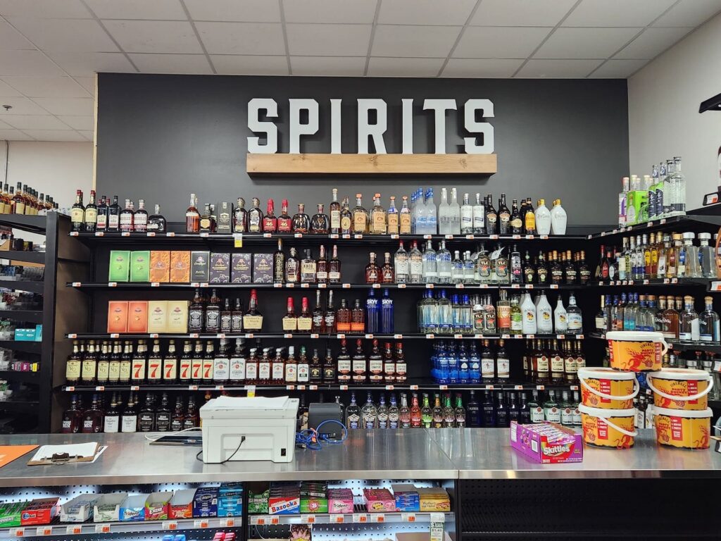 Liquor store shelves showcase spirits amid modern décor, with various items displayed on the counter in the foreground.