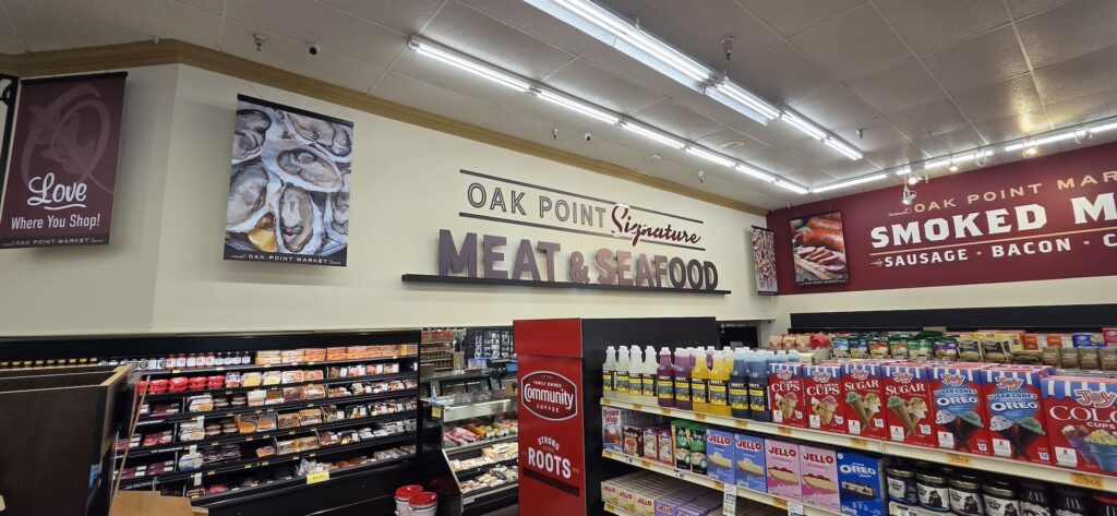 Supermarket shelves display groceries and meats, accented by retail décor and signs for 