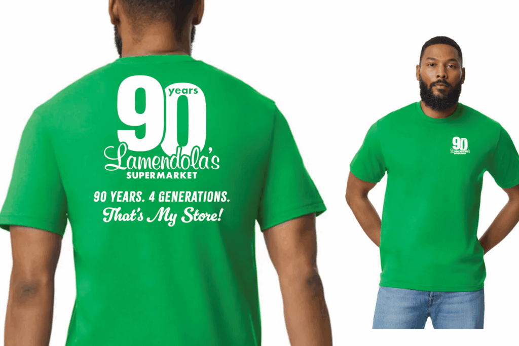 A man wears a green T-shirt with "90 years Lamendola’s Supermarket" printed on the front and back in white text.