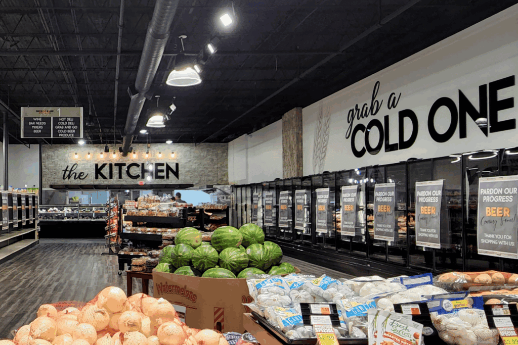 Grocery store produce section with Retail Decor; onions, watermelons, and signs reading "the KITCHEN" and "grab a COLD ONE.