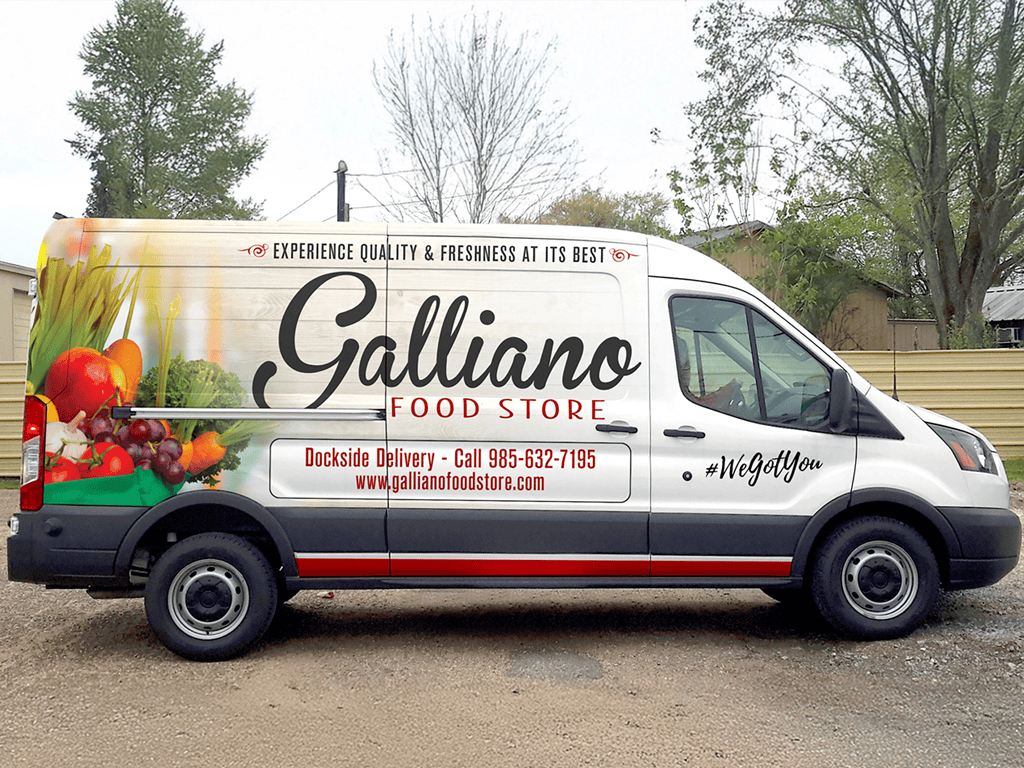 A Galliano Food Store delivery van with fresh produce images and contact information on its side, parked outdoors near trees and buildings.