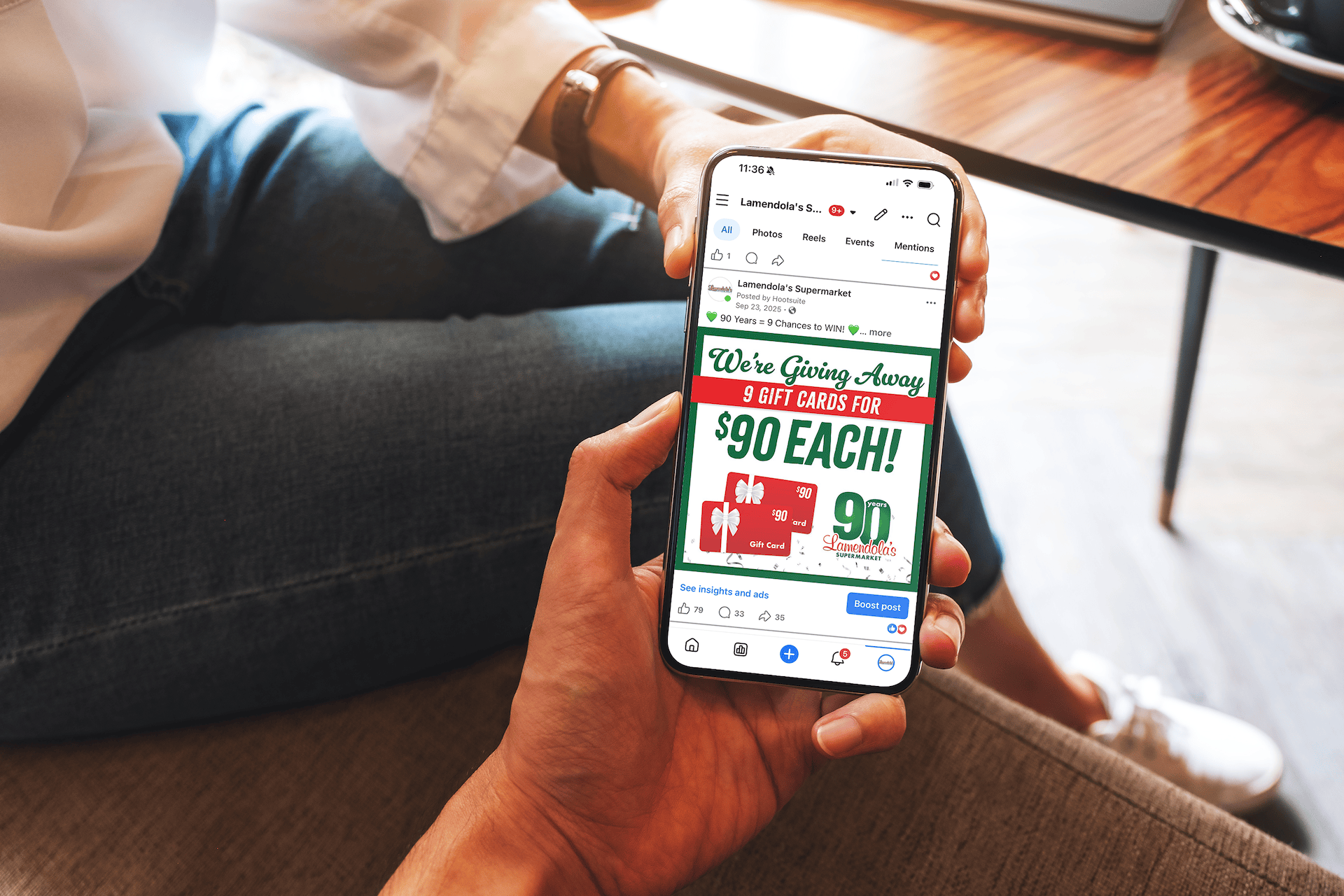 A person sits on a couch, browsing Lamendola’s 90 Years giveaway campaign on their phone via Facebook.